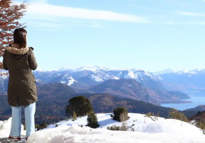 A woman looking out over a landscape of mountains and lakes